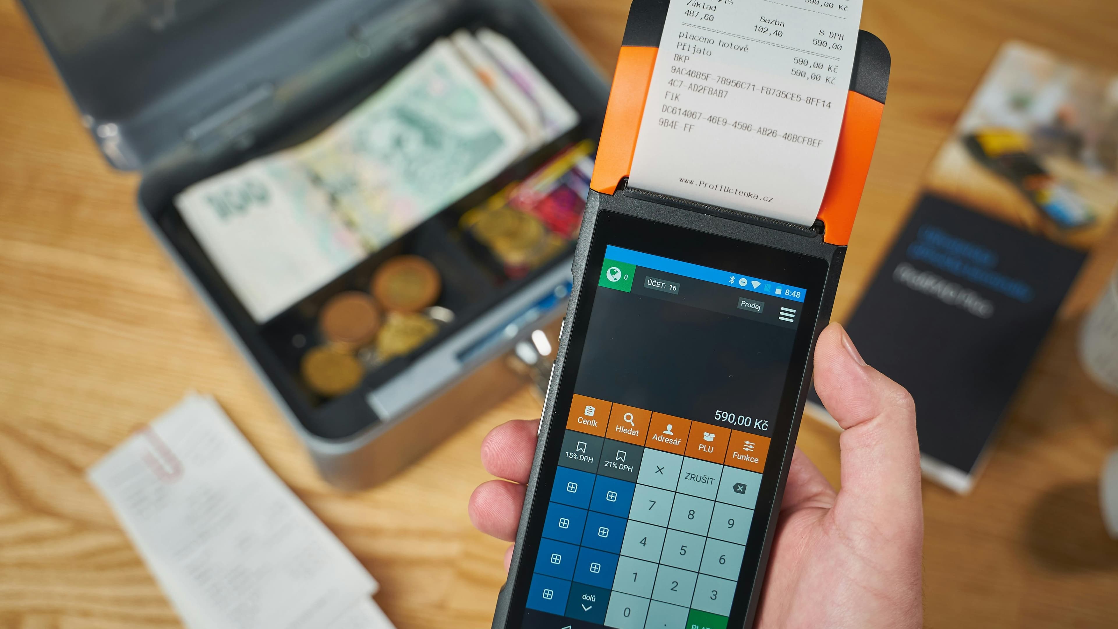 Handheld point-of-sale device beside a cash box