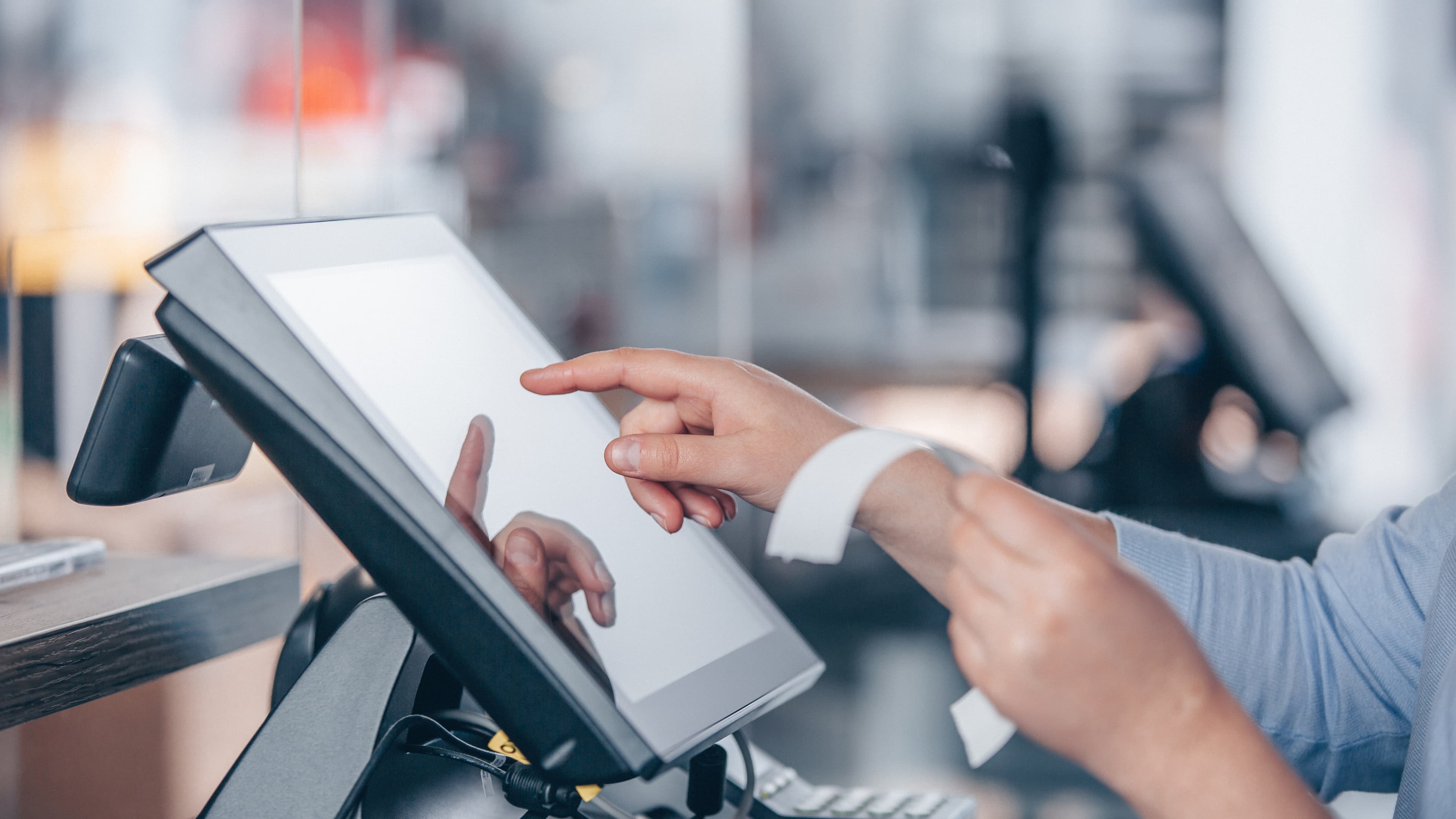 Hands using a countertop point-of-sale touchscreen
